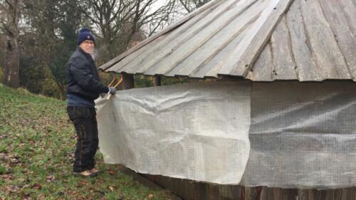 Bålhyggedagen_2021_11_28. Jan sætter presenninger op for at holde varmen inde og kulden ude